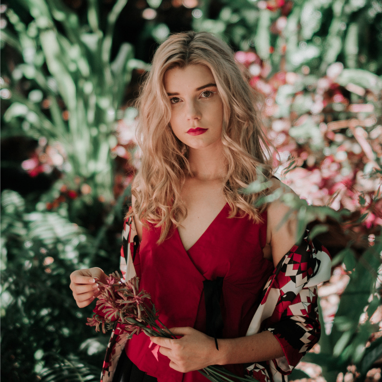 A blonde woman with flowers behind her