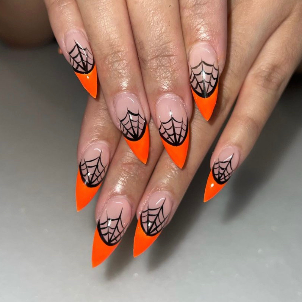 Medium length stiletto nails with orange French tips and spider webs