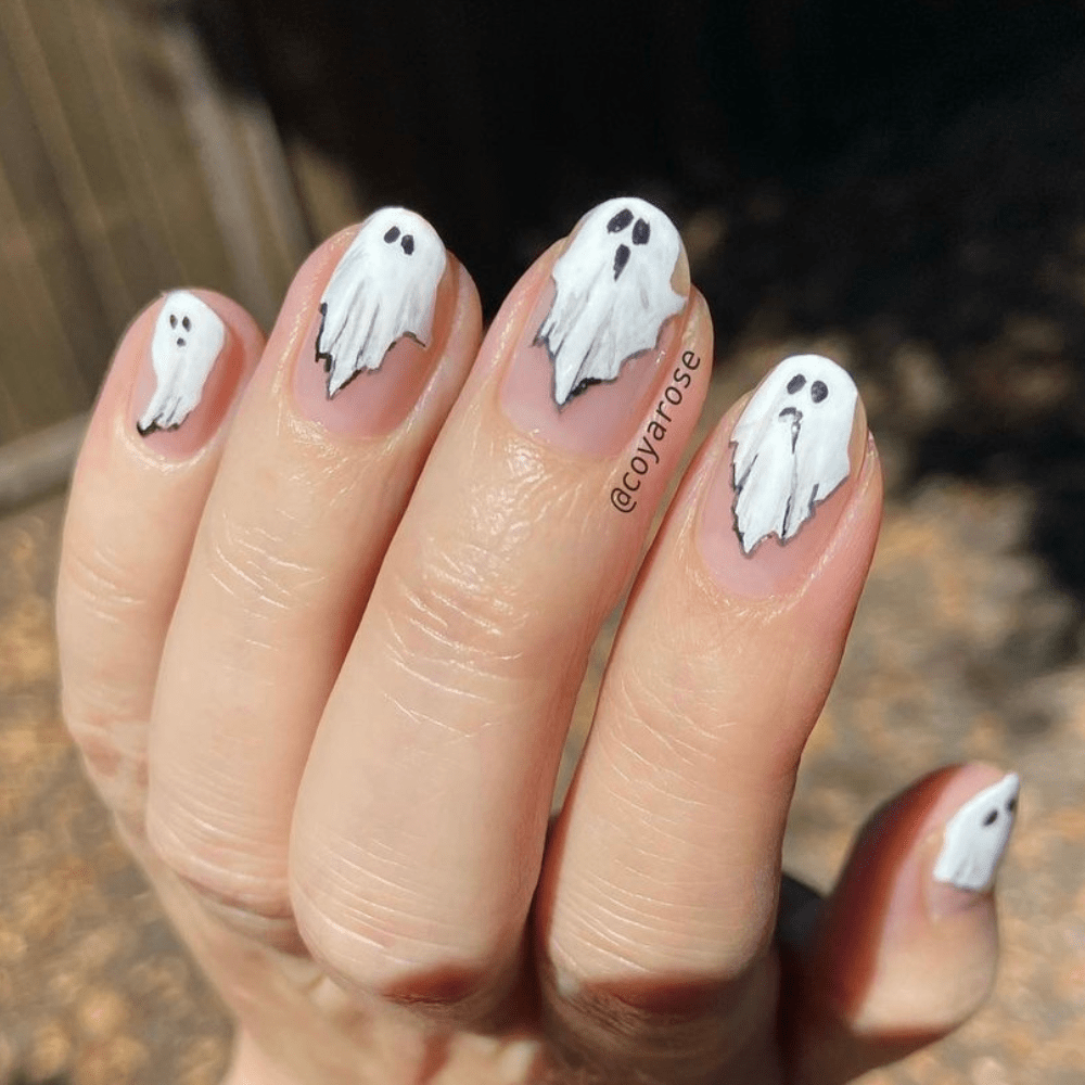 A ghost nail design with ghosts painted on the fingertips