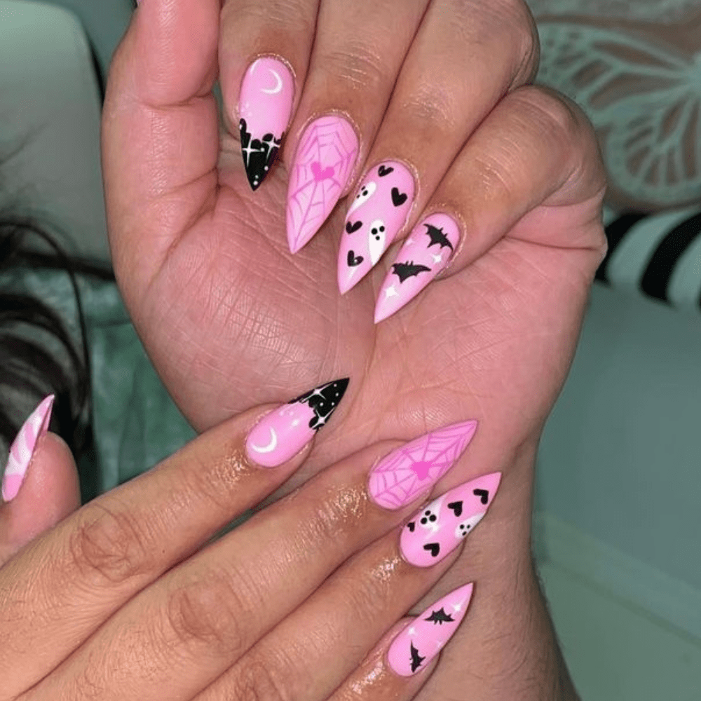 A pink and black Halloween nail design with stars, a spiderweb, ghosts, hearts, and bats