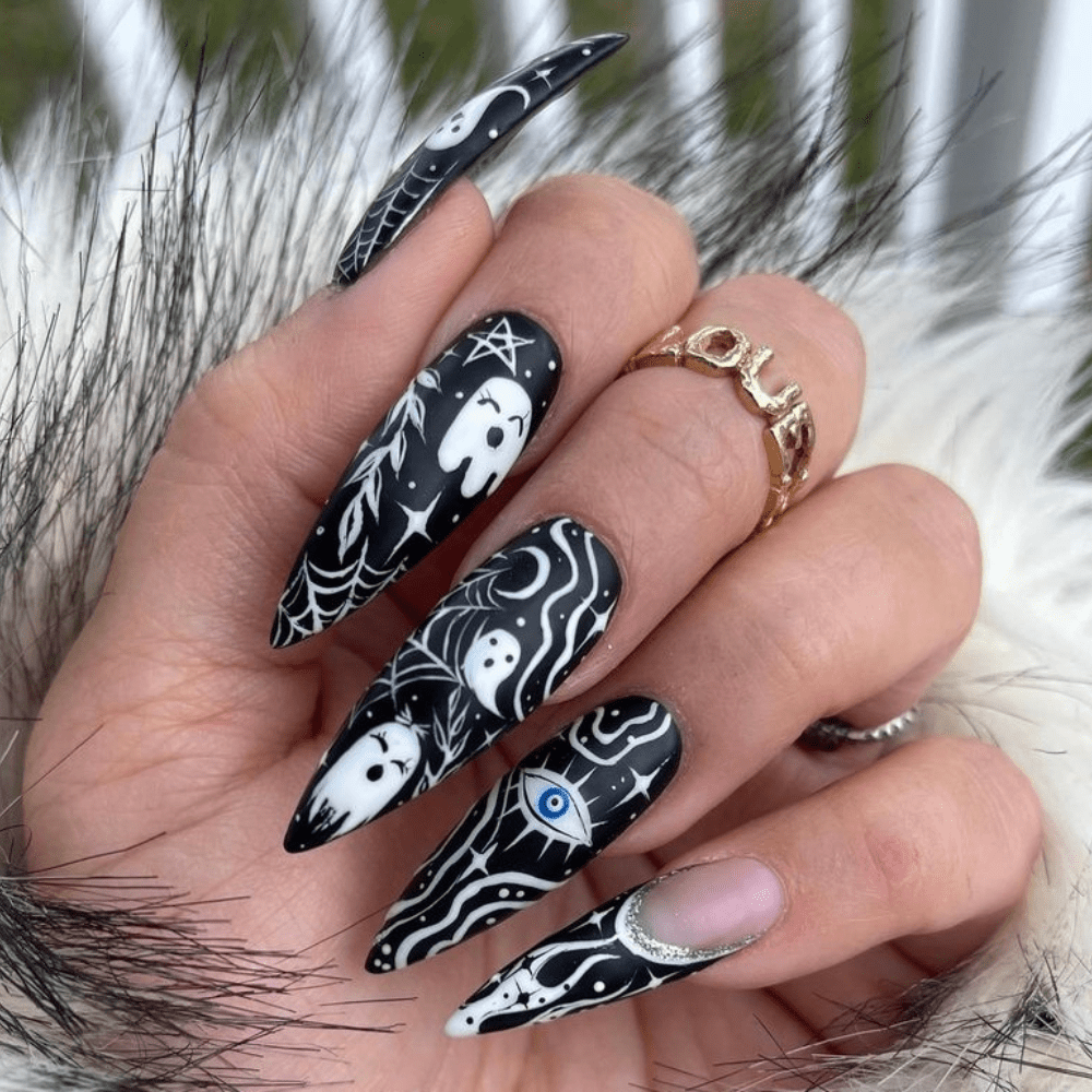 A black and white ghost nail design on long almond nails